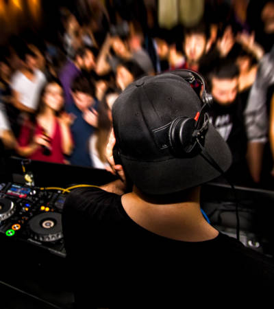 DJ with headphone and dj set at night club party. People at the